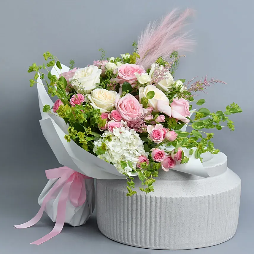 White and Pink Roses wrapped in white paper tied with pink ribbon