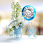 ورود بيضاء وزرقاء في مزهرية على شكل دراجة مع بالون إنه صبي