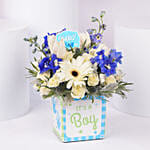 باقة ورد أبيض وأزرق في إناء مربع مكتوب عليه إنه صبي