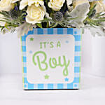 باقة ورد أبيض وأزرق في إناء مربع مكتوب عليه إنه صبي