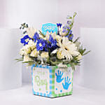 باقة ورد أبيض وأزرق في إناء مربع مكتوب عليه إنه صبي