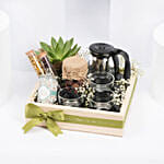 سلة خشبية فيها أبريق وأكواب شاي وكوكيز وشمعة وصبار والمزيد