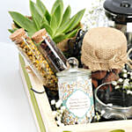 سلة خشبية فيها أبريق وأكواب شاي وكوكيز وشمعة وصبار والمزيد